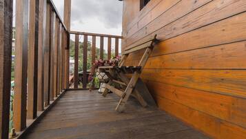 A wooden deck with a wooden bench and a small table with flowers.