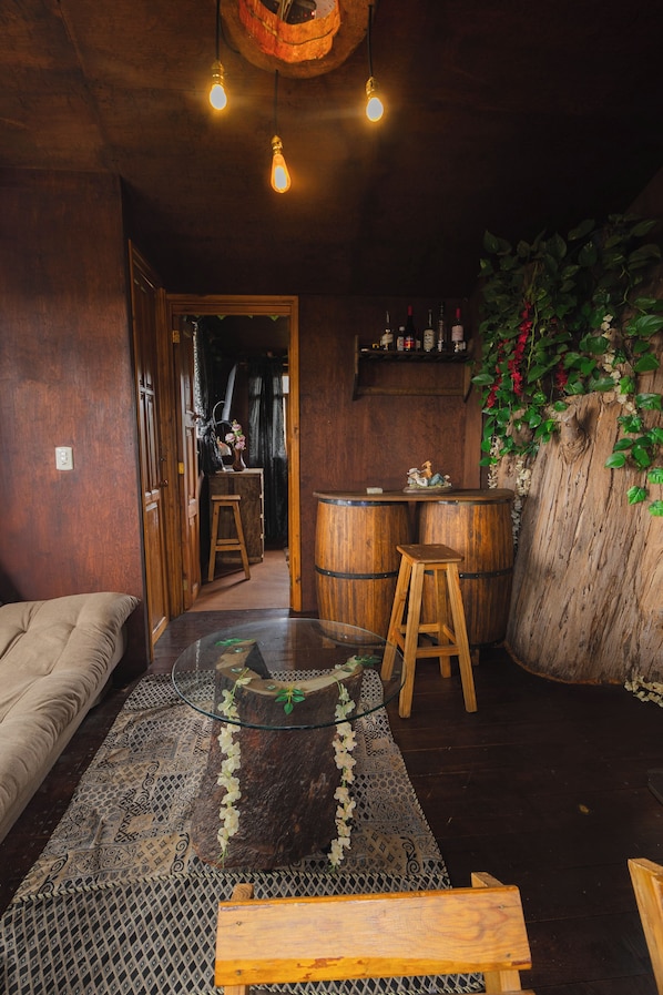Ein gemütliches Zimmer mit Holzboden, einem Glastisch, einer Bank und einer Bar mit Holzfässern.