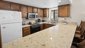 Una cocina con armarios de madera, un refrigerador blanco, un microondas, una estufa y un lavamanos.
