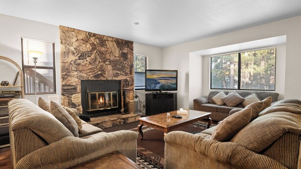 Una sala de estar con chimenea de piedra, televisor y sofá.
