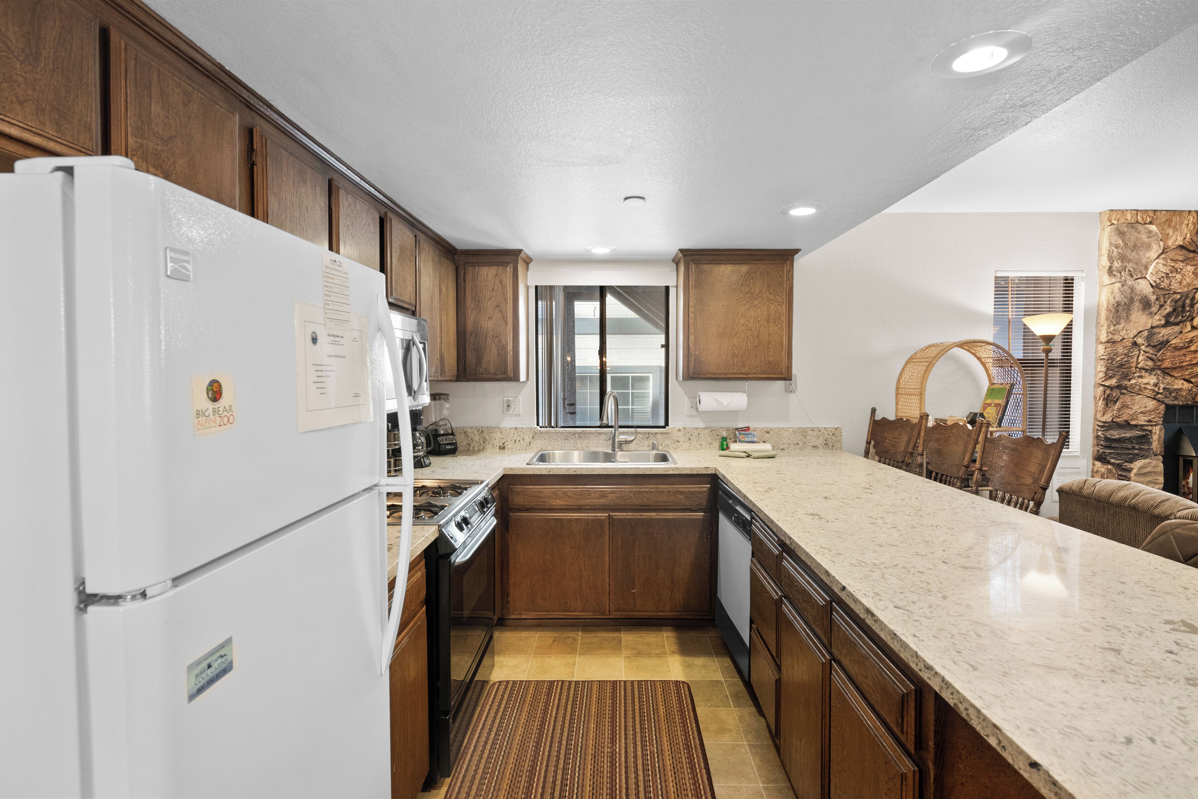 Una cocina moderna con armarios de madera, un refrigerador blanco, encimera de granito y lavavajillas integrado.