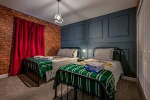 A room with two beds, a brick wall, a red curtain, and a blue wall.
