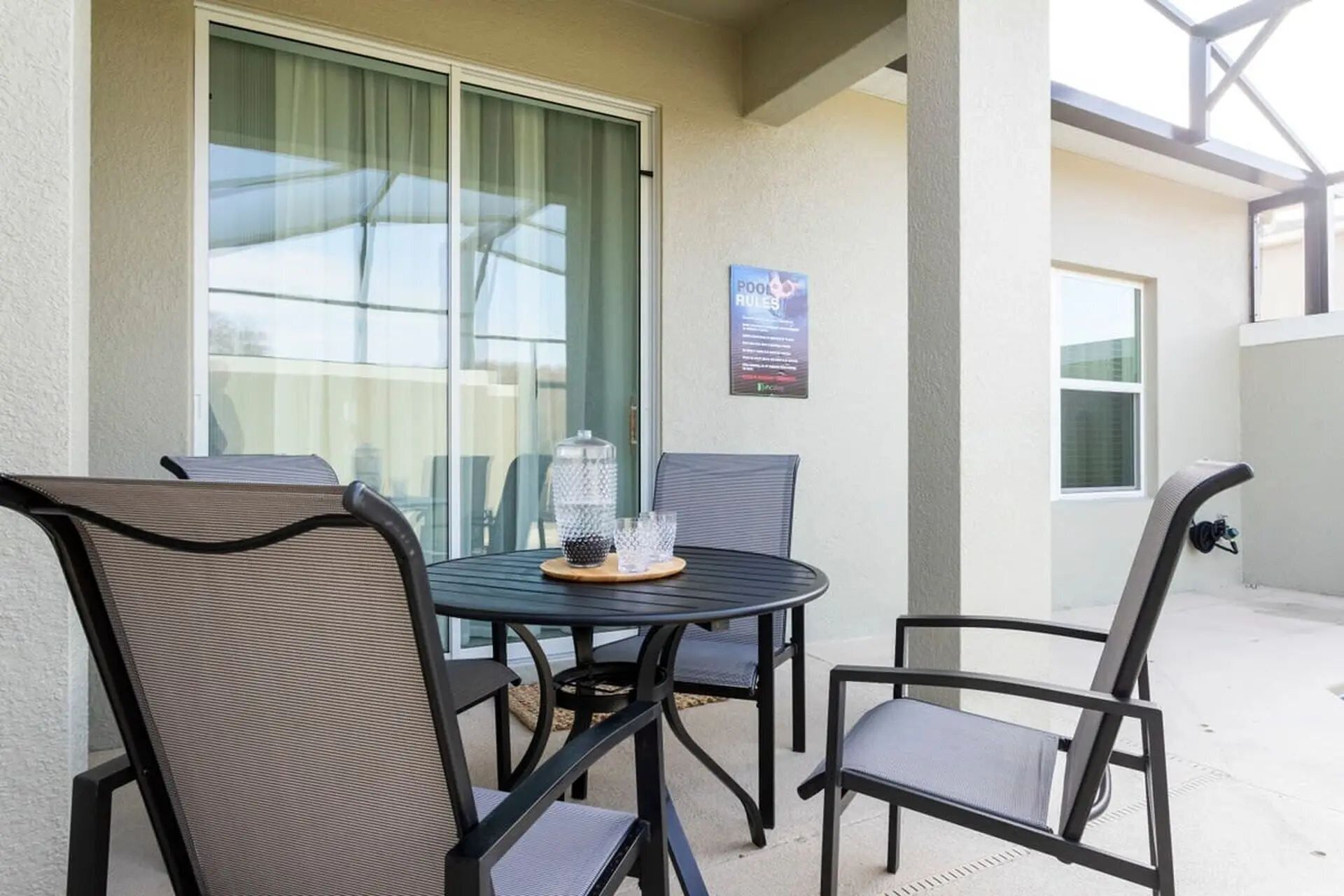 An outdoor patio with a round table and four chairs, a glass door, and a sign indicating a pool and hole 9.