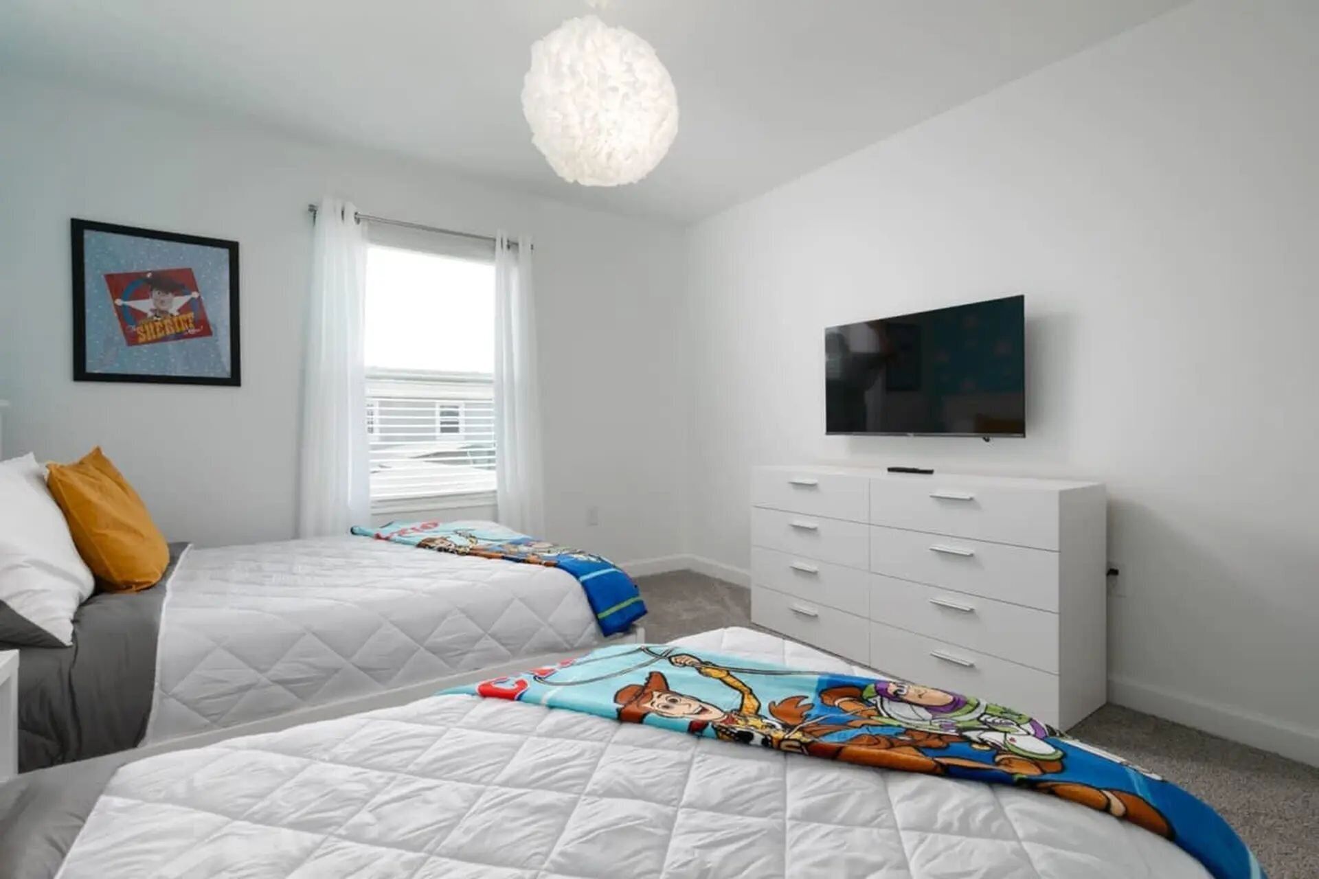 A bedroom with two beds, a TV, a dresser, and a window with blinds.