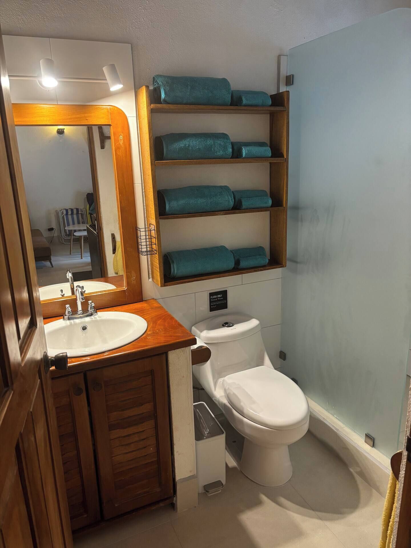Un bagno con un mobile vanitario in legno, un lavabo, un water e uno scaffale con asciugamani piegati.