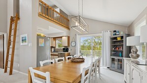 A spacious kitchen with a wooden dining table, white chairs, and a loft area above. - Drakes Island! Ocean Views!- Across from Drake's Island Beach! (Wells)