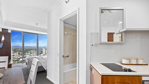 A modern hotel room with a large window offering a city view, a kitchenette with a countertop and cabinets, and a bed with a view of the city. - Comfortable Standard Studio in Surfers Paradise (Surfers Paradise)