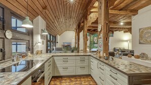 Una cocina amplia con una isla grande, vigas de madera en el techo y vistas al exterior a través de ventanas grandes.
