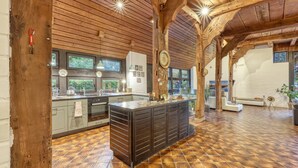 Una cocina amplia con una isla grande, vigas de madera en el techo y vistas al exterior a través de ventanas grandes.