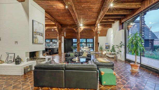 Amplia sala de estar con chimenea, un sofá grande y vistas al exterior.
