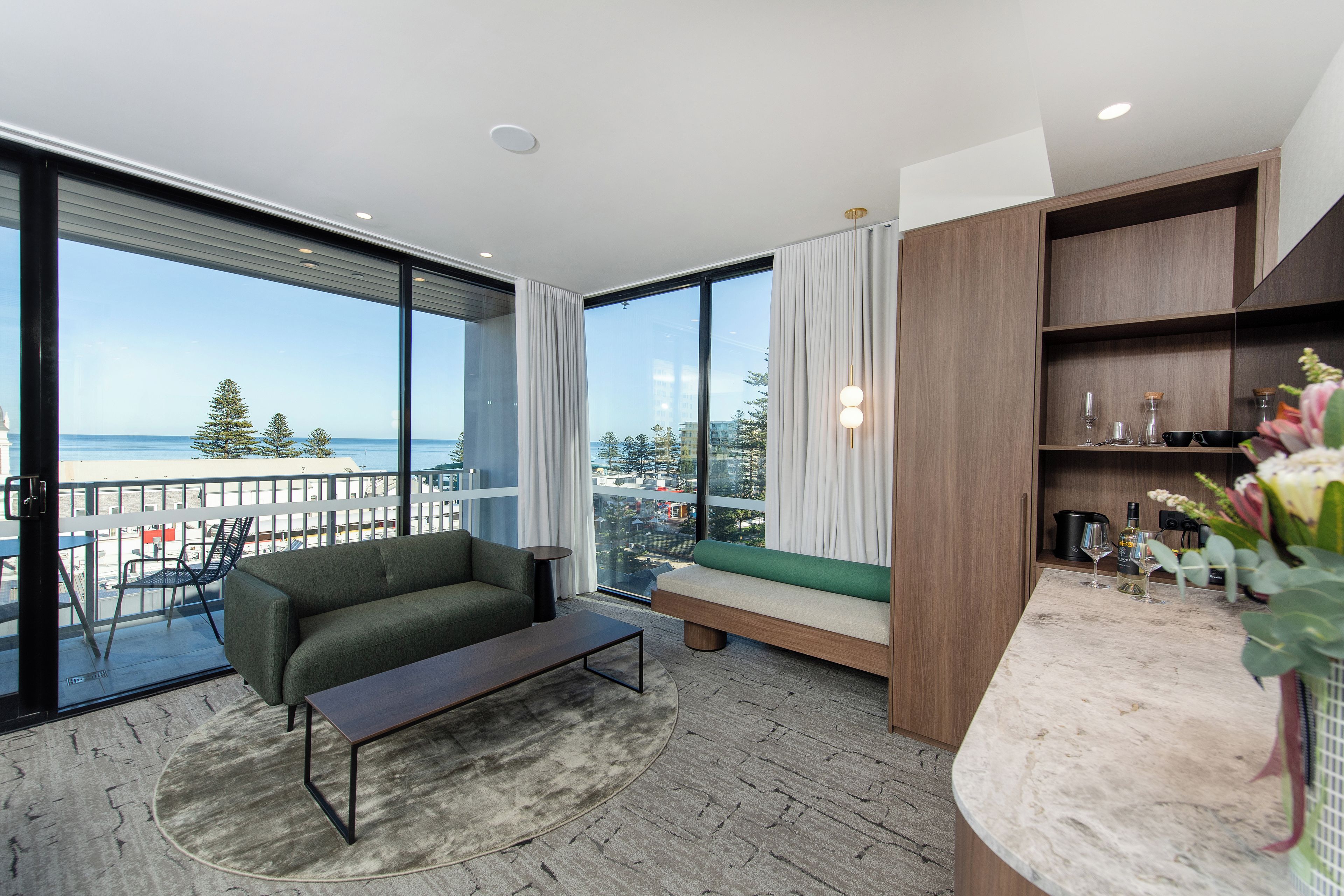 A modern living room with a sofa, a coffee table, and a view of the ocean.