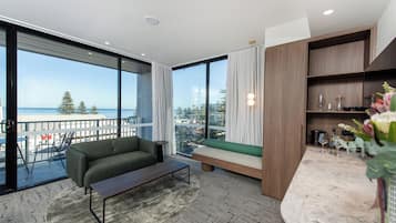 A modern living room with a sofa, a coffee table, and a view of the ocean.
