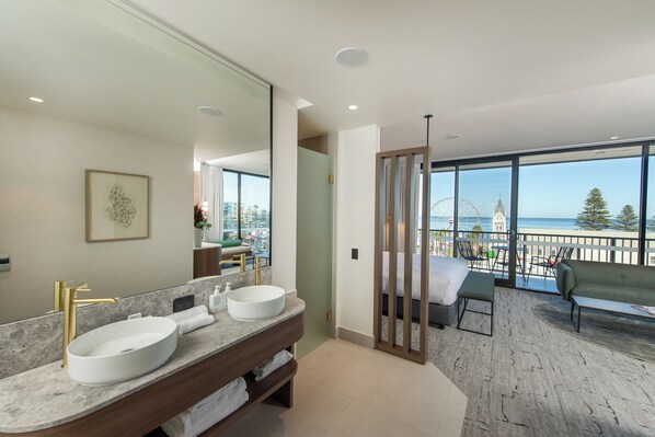 A modern bathroom with a large mirror, two sinks, and a view of the sea through large windows. - The George Glenelg (Adelaide)