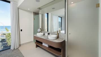 Ein modernes Badezimmer mit zwei Waschbecken, einem großen Spiegel und Blick auf den Ozean.