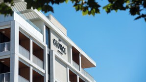 A multi-story hotel with a modern architectural design, featuring balconies and a clear sky in the background. - The George Glenelg (Adelaide)