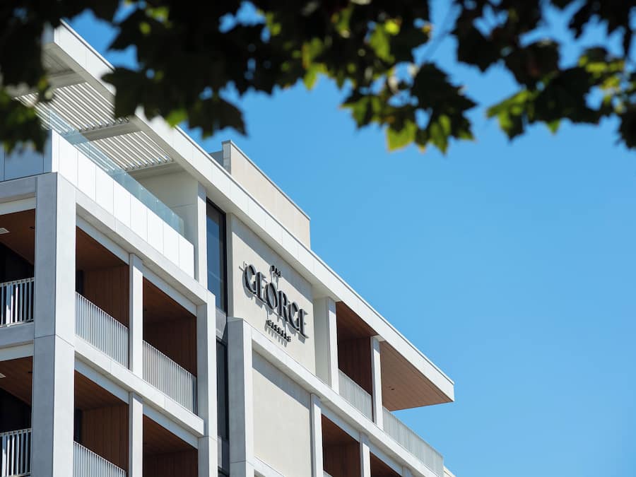 A multi-story hotel with a modern architectural design, featuring balconies and a clear sky in the background.