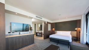 A modern hotel room with a large bed, a bedside table, a sofa, a TV, a bathroom with a mirror, and a large window. - The George Glenelg (Adelaide)