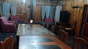 A wooden dining area with a long table and chairs, a chandelier, and curtains. - Isla de Pino Huacho (Villarrica)