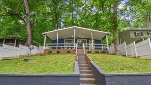 A two-story house with a covered porch, a front yard with a retaining wall, and a staircase leading to the entrance. - Riverbend Retreat (Berryville)