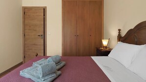 Una camera da letto con un letto, un comodino con una lampada, un armadio in legno e una porta.