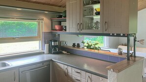 A compact kitchen with a built-in dishwasher, a coffee maker, and a window providing natural light. - Stunning home in Melby with WiFi (Melby)