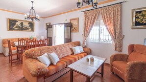 A living room with a sofa, chairs, a dining table, and a chandelier. - Alabarce Nerja by Ruralidays (Málaga)