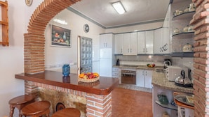 A kitchen with a brick arch, white cabinets, a granite countertop, and a fruit bowl. - Alabarce Nerja by Ruralidays (Málaga)