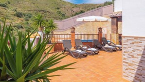 A terrace with sun loungers, a pool, and a view of a hilly landscape. - Alabarce Nerja by Ruralidays (Málaga)