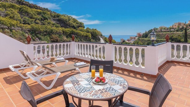 A terrace with a tiled table, two chairs, and a sun lounger. - Alabarce Nerja by Ruralidays (Málaga)