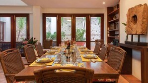 Een eetgedeelte met een lange houten tafel, gedekt voor zes personen, omringd door rieten stoelen.