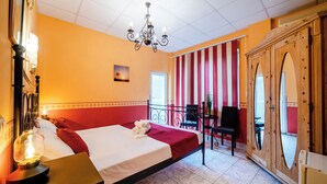Une chambre d’hôtel avec un lit, un lustre, une armoire en bois et une vue sur le balcon extérieur.