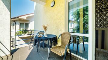 A balcony with a round table, wicker chairs, and a potted plant.