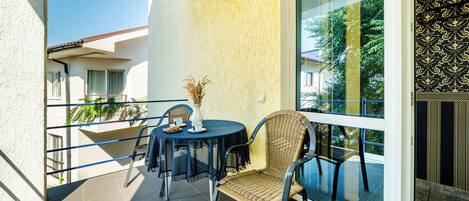 A balcony with a round table, wicker chairs, and a potted plant.