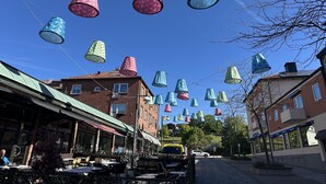 A street with buildings, outdoor seating, and hanging decorative lights. - Annex for rent – ​​Near Mallboden and Lokverkstaden in beautiful Motala |SE10023 (Motala)