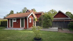 A red wooden house with a tiled roof, a green door, and a small garden with a tire planter. - Annex for rent – ​​Near Mallboden and Lokverkstaden in beautiful Motala |SE10023 (Motala)