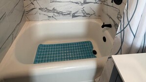 A bathroom with a bathtub, a showerhead, and a towel rack. - Two bedroom  in United States of America, Jersey City (Jersey City)