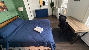 A bedroom with a bed, a desk, a chair, a dresser, a mirror, a plant, and a window. - Two bedroom  in United States of America, Jersey City (Jersey City)