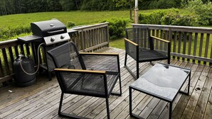 Una terraza con una parrilla, dos sillas y una mesa.
