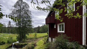 Una casa con techo inclinado, una ventana y un pequeño arroyo al frente.