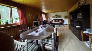 Un interior de madera con una mesa de comedor, sillas, un sofá y una estantería.