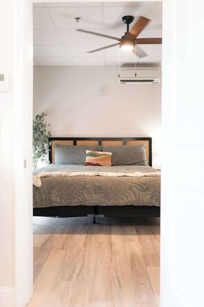 Une chambre à coucher avec un lit, un ventilateur de plafond et un appareil de climatisation.