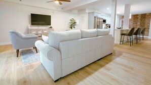 Una sala moderna con un sofá, un sillón y un televisor de pantalla plana.