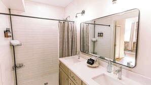 A modern bathroom with a walk-in shower, a large mirror, and a vanity with a sink and towel rack. - NEW in Downtown + free parking (Lexington)