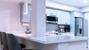 A modern kitchen with a central island, bar stools, and stainless steel appliances. - NEW in Downtown + free parking (Lexington)