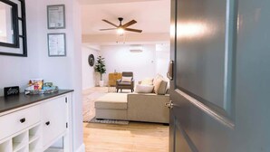 A modern living room with a sofa, a chair, and a ceiling fan. There is a small table with a plant and a framed picture on the wall. - NEW in Downtown + free parking (Lexington)