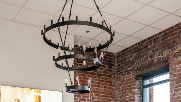 Una sala de estar moderna con pared de ladrillo, una chimenea, una lámpara redonda en el techo, un mueble aparador y un ventanal grande.