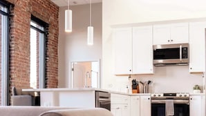 Una cocina moderna con armarios blancos, electrodomésticos de acero inoxidable y pared de ladrillo.