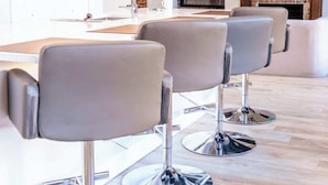 Un salón moderno con tres sillones grises, una chimenea de ladrillo y un televisor montado encima.