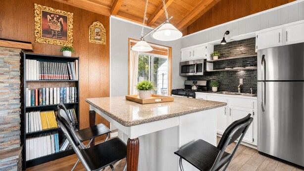 A modern kitchen with a central island, white cabinetry, and stainless steel appliances.
