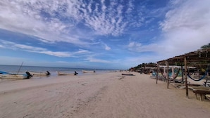 A beach with several boats, hammocks, and beach chairs. - Casa Coyote Holbox (Isla Holbox)